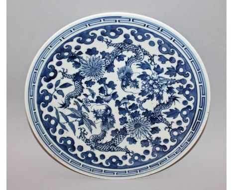 A 19TH CENTURY CHINESE BLUE & WHITE PORCELAIN DRAGON DISH, painted with two confronting dragons amidst foliage, 11in diameter