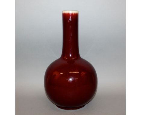 A LARGE CHINESE SANG-DE-BOEUF PORCELAIN BOTTLE VASE, the lightly streaked glaze thinning at the top rim, the base with a Qian