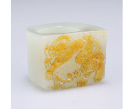 A CHINESE JADE THUMB RING, the plaque front carved with a chilong displaying russet inclusions. Front 3.6cm wide