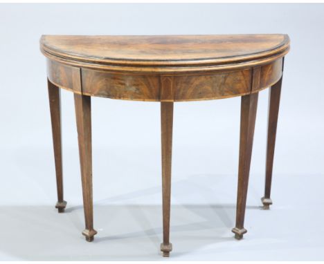 A GEORGE III MAHOGANY FOLDOVER CARD TABLE, demilune, the string inlaid and crossbanded top opening to reveal a green baize li