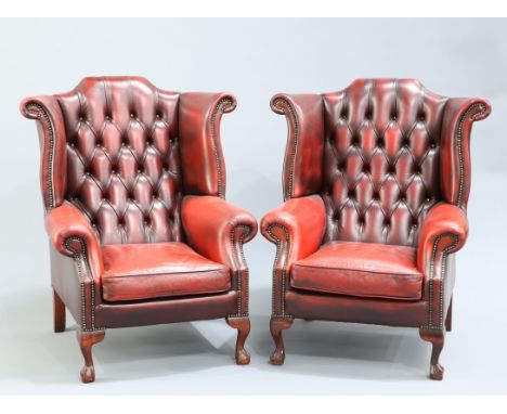 A PAIR OF OXBLOOD LEATHER WING-BACK ARMCHAIRS, each with deep button back and ball and claw feet.&nbsp;