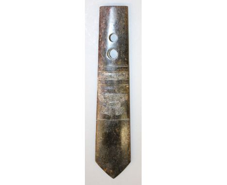 A 20TH CENTURY CHINESE JADE-LIKE AXE, carved with archaic designs, the stone of predominantly brown tone, 11in long.