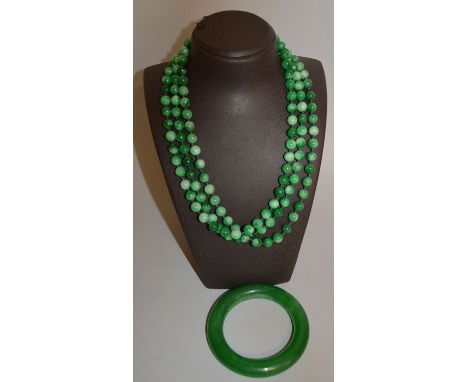 TWO GREEN JADE NECKLACES AND A BANGLE.
