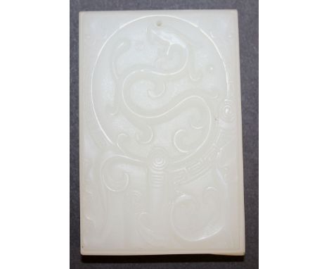 A CHINESE WHITE JADE-LIKE PENDANT, decorated to its front with a stylised dragon within a key-fret border, 2.9in x 1.9in x 0.