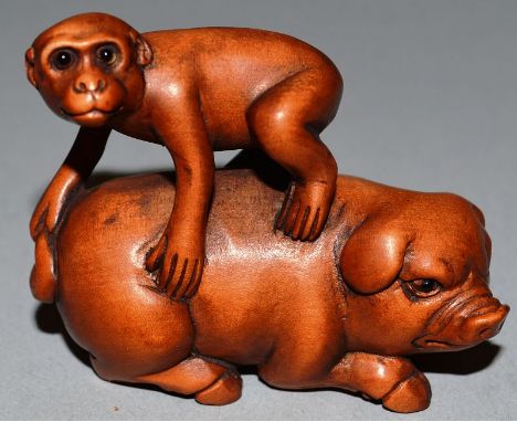 A BOXWOOD CARVED NETSUKE, A MONKEY ON A PIG’S BACK, signed.