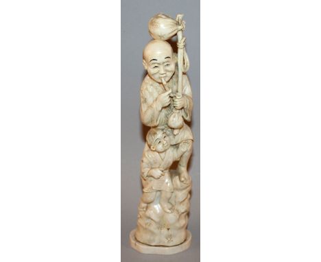 A SIGNED EARLY 20TH CENTURY JAPANESE IVORY OKIMONO OF A MAN & BOY, standing on rockwork, the man holding a pipe, 10.25in high