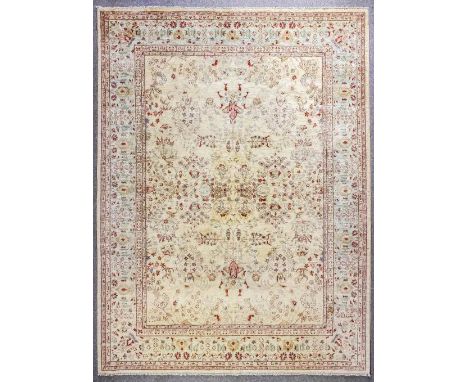 A modern Persian style carpet, woven in muted colours with all over floral motifs on a pale fawn ground, within conforming bo