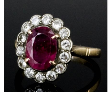 A 1960s 14k white and yellow gold mounted ruby and diamond ring, the oval cut ruby approximately 1.5ct within a border of fou