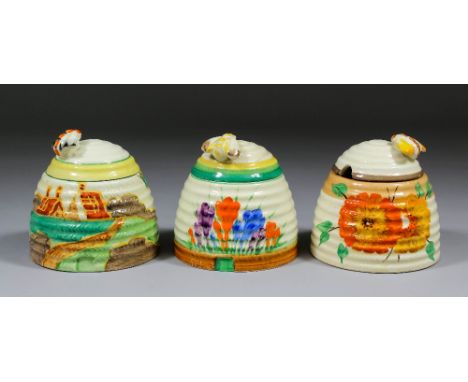 Three Clarice Cliff pottery honey jars and covers, comprising  - "Secrets (Fantasque)", "Autumn Crocus" both with Newport bac