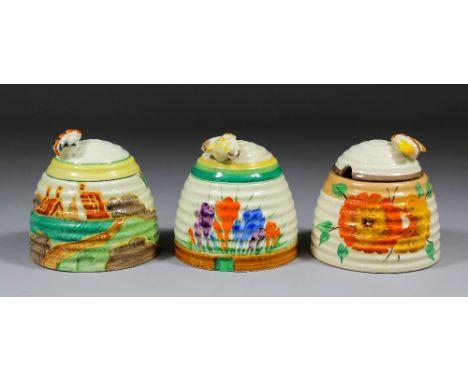 Three Clarice Cliff pottery honey jars and covers, comprising  - "Secrets (Fantasque)", "Autumn Crocus" both with Newport bac