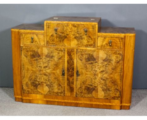 A 1930's walnut and figured walnut sideboard/ cocktail cabinet the central section opening to reveal mirrored interior, flank