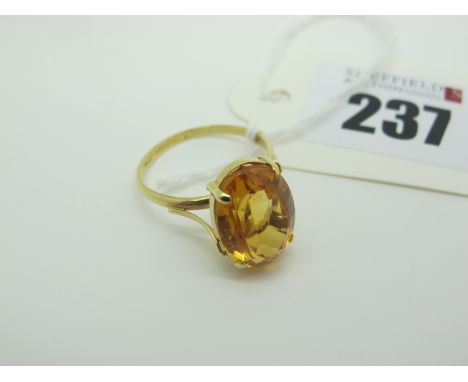 A Citrine Single Stone Dress Ring, oval four claw set high between stylised shoulders, stamped "750" (finger size Q) (3.6gram