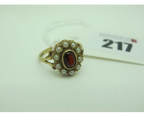 A Pearl and Garnet Oval Cluster Ring, of antique style, between bifurcated shoulders (finger size P). 