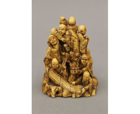 A carved ivory netsuke worked with various figures, signed