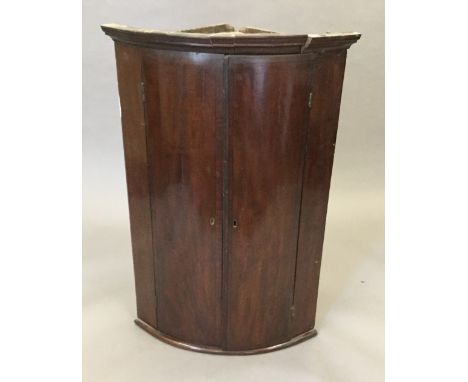 A George III mahogany bow front hanging corner cupboard with painted interior.  67 cm wide.