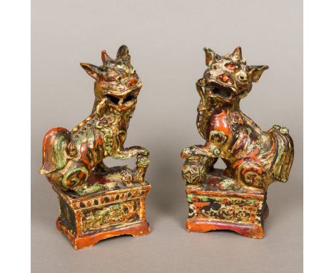 A pair of Chinese antique polychrome and gilt decorated pottery temple lion incense stick holders, each typically moulded sea