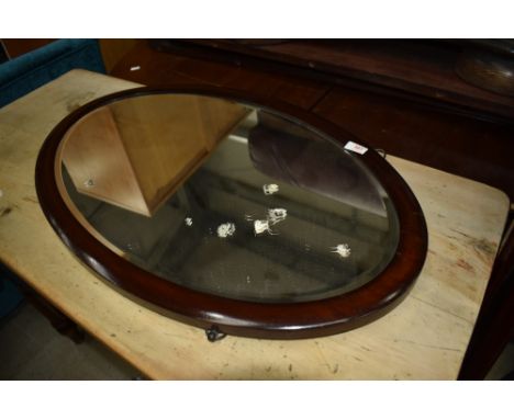 An early 20th Century mahogany framed oval wall mirror, hung in portrait orientation, approx 75 x 47cm