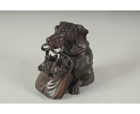 A BLACK FOREST CARVED WOOD DOG carrying three puppies in a basket, formed as an inkwell. 4.5ins high.