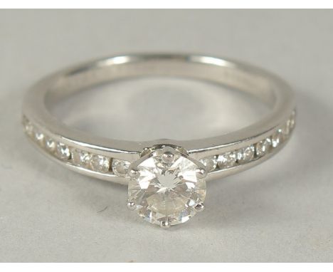 A TIFFANY &amp; CO. PLATINUM AND SINGLE STONE DIAMOND RING with seven small diamonds on the shoulder. Marked Tiffany &amp; Co