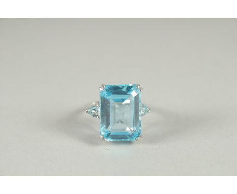 A LARGE SILVER EMERALD CUT TOPAZ RING.