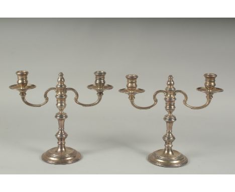 A PAIR OF SILVER TWO LIGHT CANDLESTICKS on circular bases.  9ins high.