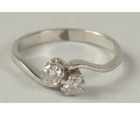 A PLATINUM AND DIAMOND TWO STONE CROSS OVER RING Ring size K.