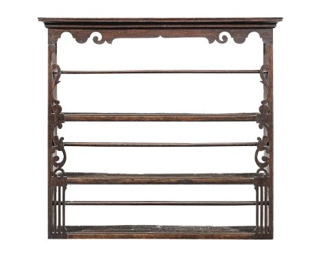 A George III oak delft rack, circa 1780Having three open-shelves, each with a retaining bar, below a flattened-arch and scrol