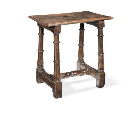 A walnut joint stool, French, circa 1700The ovolo-moulded top centred by a small S-shaped carry-aperture, on columnar and bal