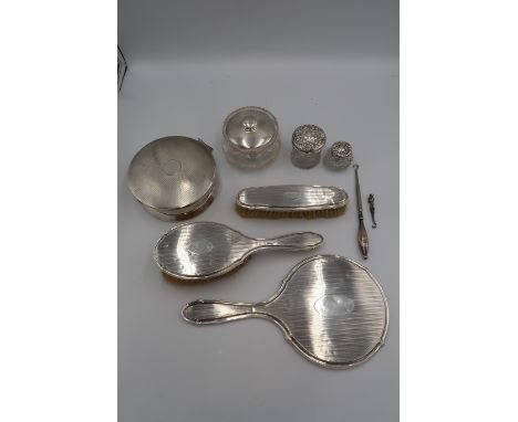 A silver backed dressing table vanity set, comprising hairbrush, clothes brush and mirror, with engine turned decoration and 