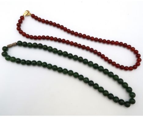A nephrite jade bead necklace Weight 41.47 grams. Together with a brown bead necklace. Weight 22.57 grams.