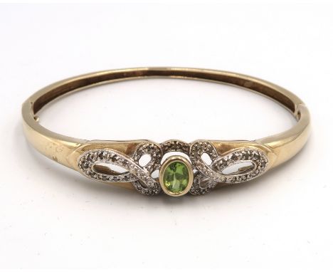 A peridot and diamond hinged bangle. Tests gold 9ct. Stamped 0.25. Weight 12.13 grams.
