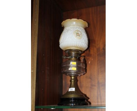 AN OIL LAMP WITH CLEAR GLASS RESERVOIR WITH LATER SHADE 