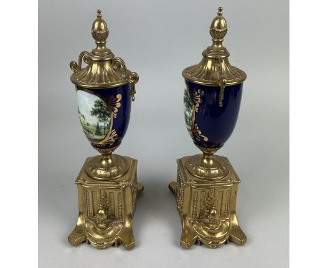 A PAIR OF FRENCH CERAMIC AND GILT METAL URNS PAINTED WITH LANDSCAPE SCENES