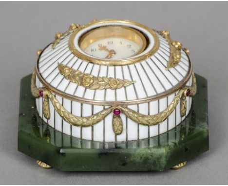 An unmarked gold and ruby set white enamel decorated desk clock
Of domed form, standing on a spinach jade base with bun feet.