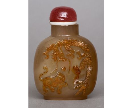 A Chinese carved russet jade snuff bottle
Of typical form, the front decorated with a dragon and a dog-of-fo chasing a pearl,