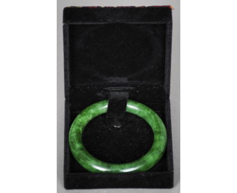 A Chinese carved green jade bangle
Of typical form, in fitted case.  9 cm diameter. CONDITION REPORTS: Generally in good cond