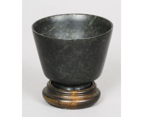 A Chinese spinach jade tea bowl
Of typical form, standing on a plinth base.  6 cm high. CONDITION REPORTS: Overall good, some