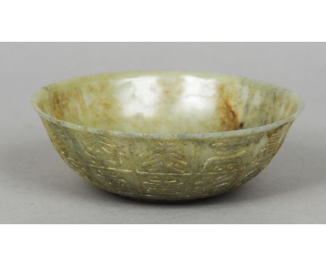 A Chinese carved green and russet jade bowl
The exterior worked with archaic script.  15 cm diameter. CONDITION REPORTS: Gene