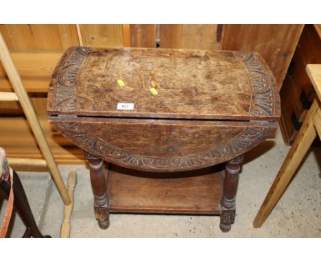 A carved oak gate leg occasional table with rounded drop leaves and under tier 