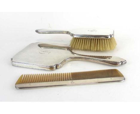 A silver backed hand mirror, comb and hairbrush, maker RC, London 1929/30 (3) CONDITION REPORT: Dents, wear and personalised 