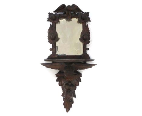 A Black Forest-type carved wall mirror with a shelf and figural support, h. 94 cm