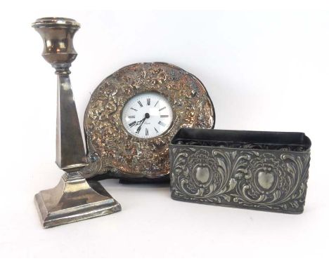 A silver mounted repousse decorated easel back clock with quartz movement, London 1990, h. 16 cm, together with a silver cand