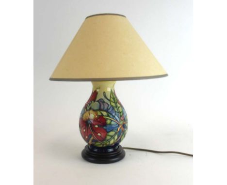 A Moorcroft table lamp of ovoid form decorated with hibiscus on a shaded blue ground, h. 35 cm including shade and fitments C