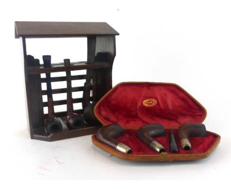 A pipe rack modelled as a wishing well containing three assorted pipes together with a Barling's crocodile skin cased set of 