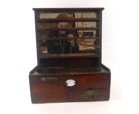 A 19th century mahogany tobacconist/publican's till, the mirrored back with shelves for stacking coins, over two slots with a