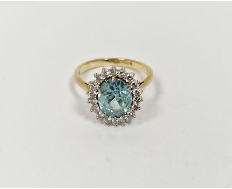 18ct gold yellow gold, diamond and blue stone ring, the oval central stone aquamarine in colour surrounded by claw set diamon