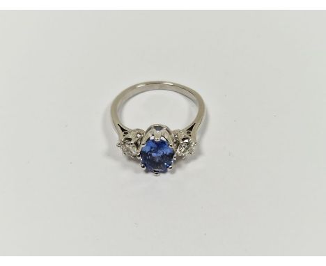 White metal, diamond and blue stone dress ring set central oval blue stone, possibly tanzanite, flanked by two brilliant cut 