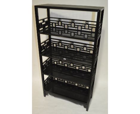 A Chinese design black lacquered floor standing open display stand, with 4 fitted shelves and pierced fretwork decoration, wi