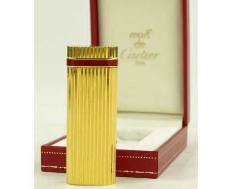 A Cartier gold plate and red enamel pocket lighter, length 7cm, boxed with papers.