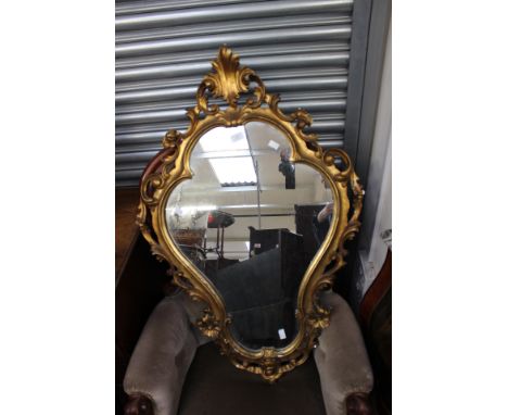 A gilt gesso framed mirror with scrolling and floral design 